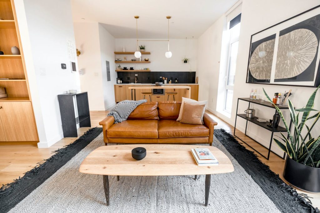 Stylish modern living room with a leather sofa, kitchen area, and decor elements.