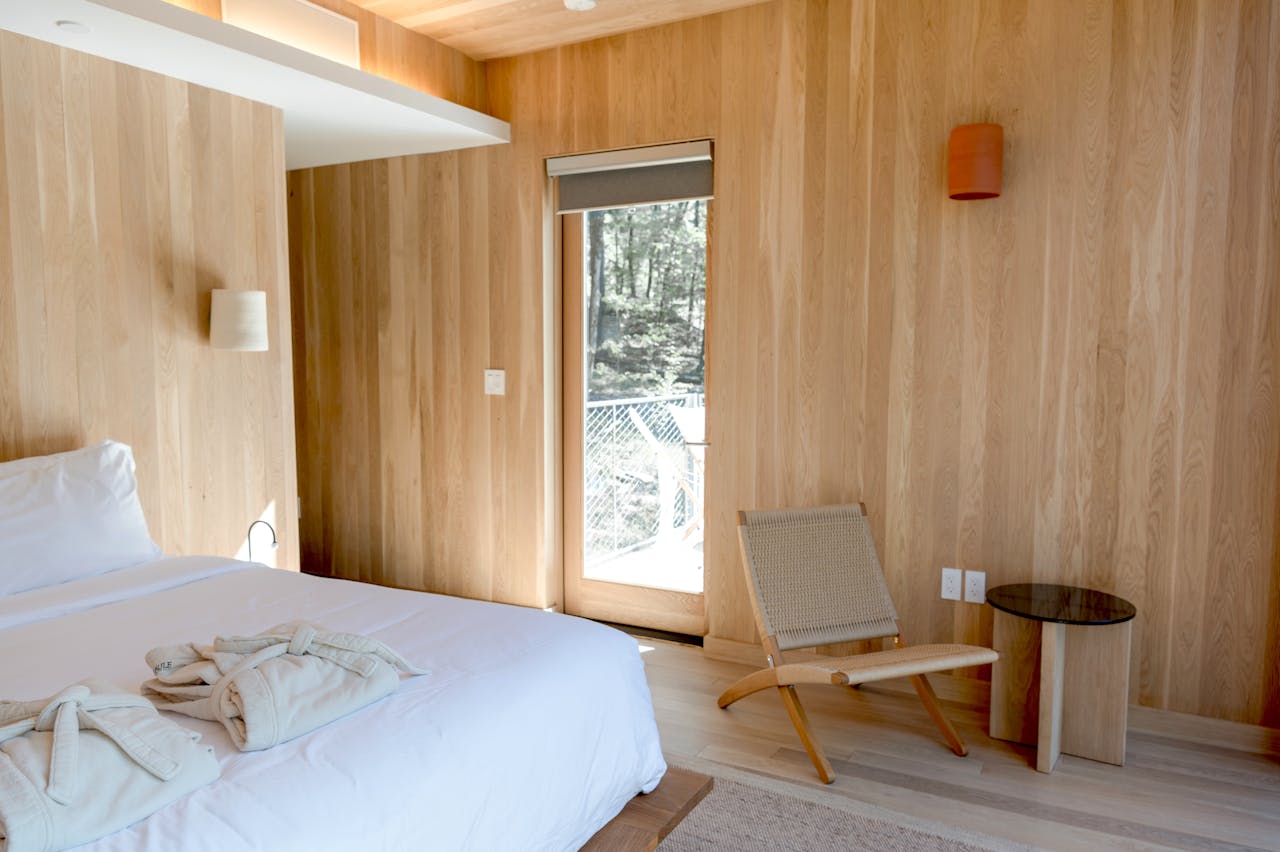 Bright minimalist bedroom featuring wooden walls and flooring in Catskill, NY.